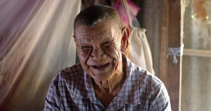 An Asian man who is more than seventy years old and works as a wage earner in a farm, live in an old house, smiling and laughing happily. 