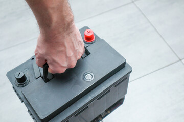 Close-up hand of a mechanic in a service center picking up a new battery to replace the car....