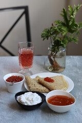 Tiny crepes on a plate. Crepes with salmon caviar. Savory food close up photo. Traditional French pancakes. 