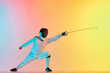 Long attack. Young man, male fencer with sword practicing in fencing over gradient pink-yellow background in neon light. Sportsman shows fencing technique