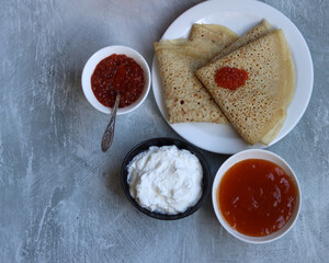 Tiny crepes on a plate. Crepes with salmon caviar. Savory food close up photo. Traditional French pancakes. 
