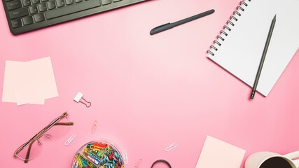 Modern workspace with coffee cup, keyboard and notebook on pink background. Top view. Flat lay