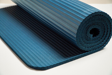 Rolling on blue exercise mat and preparing for yoga on white background,sports accessories. banner