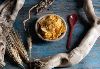 piattino di corn-flakes con cucchiaino rosso su sfondo celeste