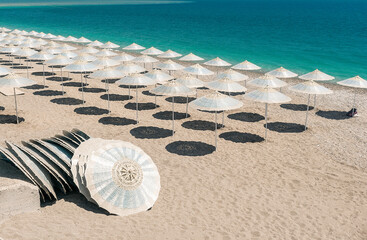 Fototapeta na wymiar A row of beach umbrellas in blue color on the seashore with turquoise water.