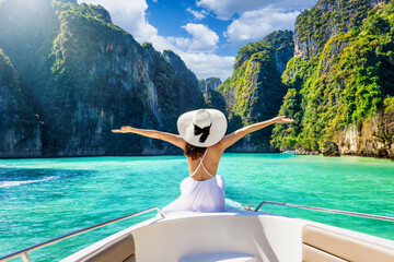 Happy tourist woman in white summer dress relaxing on boat at the beautiful Phi Phi islands, Tourism Phuket, Krabi, travel concept for Thailand