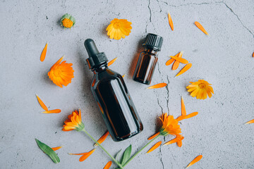 Top view of glass bottles of calendula essential oil with fresh marigold.