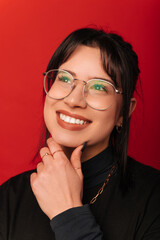Vertical portrait of a young dreaming woman holding hand near her chin.