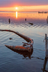 Boat wreck on sunset with reflection on sea water and beautiful colors