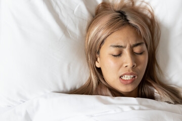 Tired and stressed Asian woman with colored hair sleeping, having bad dream, nightmare with bruxism...