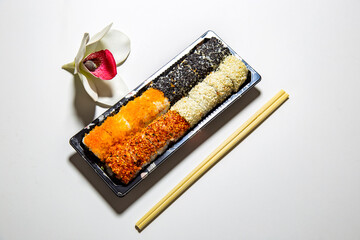 sushi rolls set with wooden chopsticks and orchid on white background