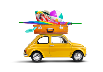 Retro yellow car with luggage and beach equipment on the roof. Summertime vacation road trip concept.