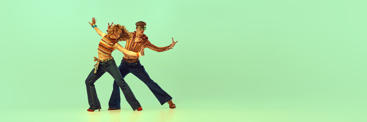 Incendiary dance. Emotional man and woman in retro style clothes dancing disco dance over green background. Concept of fashion trends of 70s, 1980s years, music