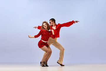 Young beautiful couple of dancers in bright retro fashion clothes, stage costumes dancing over...
