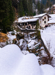 Sappada, Italy - December 30, 2022: Idyllic winter photo of abandoned water mill in Sappada, an alpine village on the edge of the Italian Dolomites