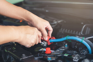 Close up hand service man use wrench lock bolt of Battery terminal after change new car battery in engine room , service concept and car mainternance