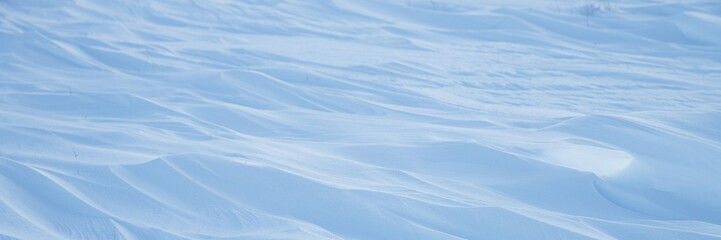 Snow texture. Wind sculpted patterns on snow surface. Wind in the tundra and in the mountains on the surface of the snow sculpts patterns and ridges. Arctic, Polar region. Winter panoramic background.