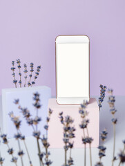 Mobile phone with blank white screen on podium with lavender flowers. Smartphone screen with copy space for logo, sale promotion, design, social media, shopping and business, spring concept