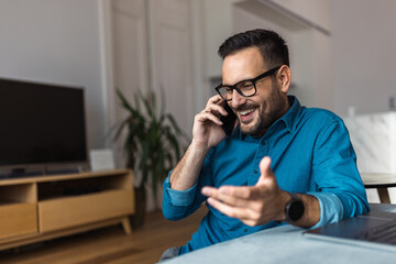 Smiling businessman making a phone call with a client, sitting at the home office.
