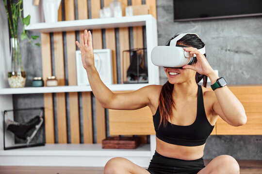 A fitness woman uses a VR device to get motivated during a workout at home.
