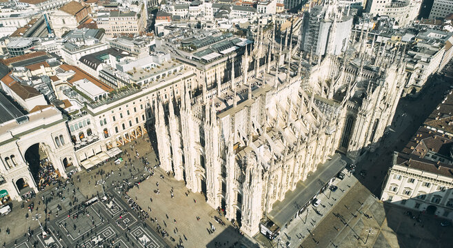 Aerial view of Piazza Duomo in front of the gothic cathedral in the center. Drone view of the gallery and rooftops during the day. Milan, Italy. High quality photo