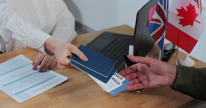 Close-up of a woman travel agent gives passports with plane tickets to a man. Travelling concept.