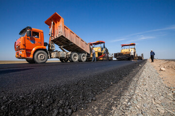 Fototapeta na wymiar Kyzylorda province, Kazakhstan, April 29, 2012: Dump truck unloads hot asphalt. Construction of West Europe-West China new highway