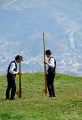 Two men preparing their alphorns to playing, they put them on special support, Swiss Alps, Nendaz,...