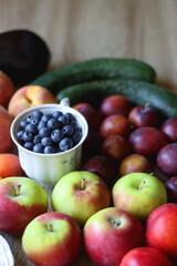 Berries in vintage porcelain dishes, other healthy fruit and vegetable on wooden table. Selective focus.