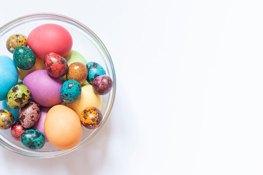 Colorful painted Easter eggs in the glass bowl on the white background. Close up. Copy space