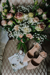 Fototapeta na wymiar Wedding bouquet of the bride of pink flowers roses and greenery, beige shoes, perfume, earrings, and ring on chair background. Bride accessories. Letters from the bride and groom. flat lay. top view.