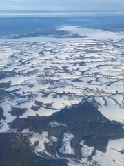 View from the plane window to the snow-covered expanses with ravines.