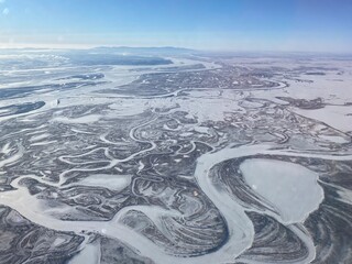 Abstract winter panorama with snow-covered territory - forests, fields and winding rivers.