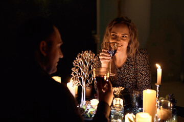 A romantic couple sharing a candlelit dinner. The dimly lit room creates an intimate atmosphere...
