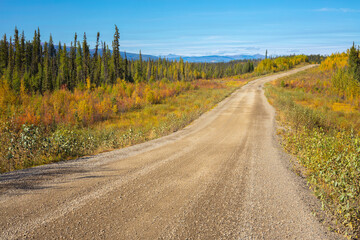 Fototapeta premium Gravel road in the endless boreal forest of Yukon Territory, Canada