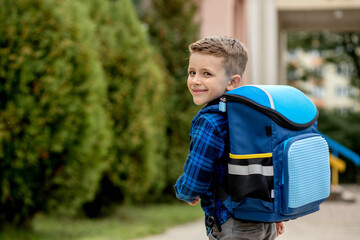 Little first grader with a blue backpack goes to school