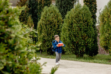 Fototapeta premium Little first grader with backpack looking the copybook, going home from school