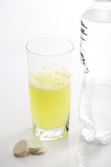 The effervescent tablet dissolves in a glass of water.