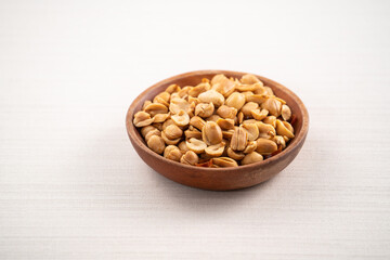 Spicy flavored peanut kernel in a bowl on white table background.
