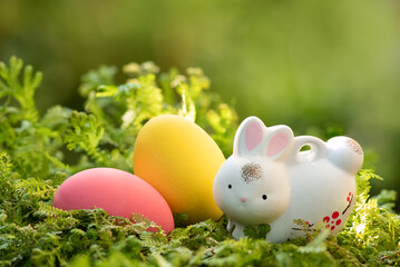 Fototapeta na wymiar Easter eggs and ceramic rabbit on nature boken background.