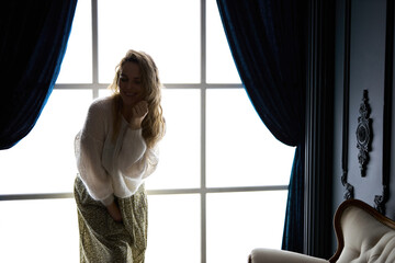 Stylish young woman in modern interior in the contrasting light of a glowing window