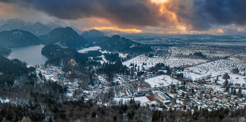 Aerial view of the Neuschwanstein Castle or Schloss Neuschwanstein on a winter day, with the mountains and trees capped with snow all around it. - obrazy, fototapety, plakaty