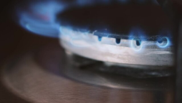 Setting fire of a gas-ring close up. Home gas stove burner starts to burn with blue flame. Using home gas cooking equipment. Natural fuel flame