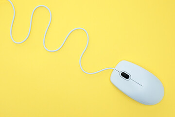 White modern wired computer mouse on yellow background