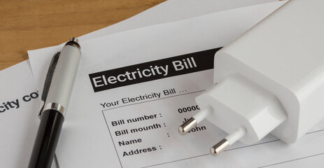 electrical outlet , pen and electricity bill on the wooden table 