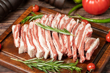 Fresh raw lamb spare ribs. Uncooked sliced lamb ribs on a wood serving board. Close up