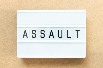 Lightbox with word assault on wood background