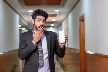 Young businessman giving shocking expression while showing smartphone screen