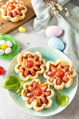 Idea for Easter breakfast or lunch. Mini pizza. Pizza in puff pastry with cheese and tomatoes on the festive table.