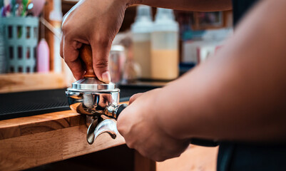 Close-up of hand Barista cafe making coffee with manual presses ground coffee using tamper at the coffee shop
